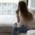 Lonely woman sitting on couch in living room, looking away